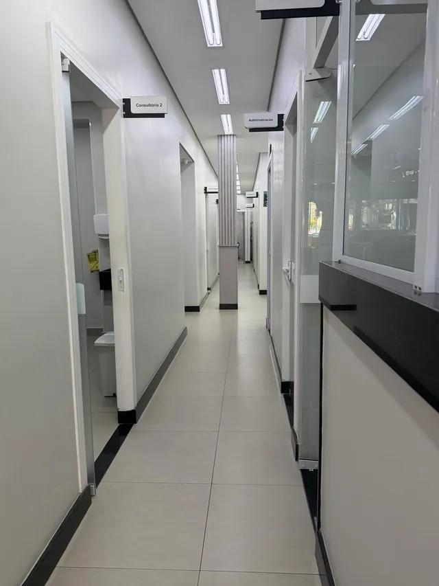 Corredor branco com as portas dos consultórios identificadas por placas