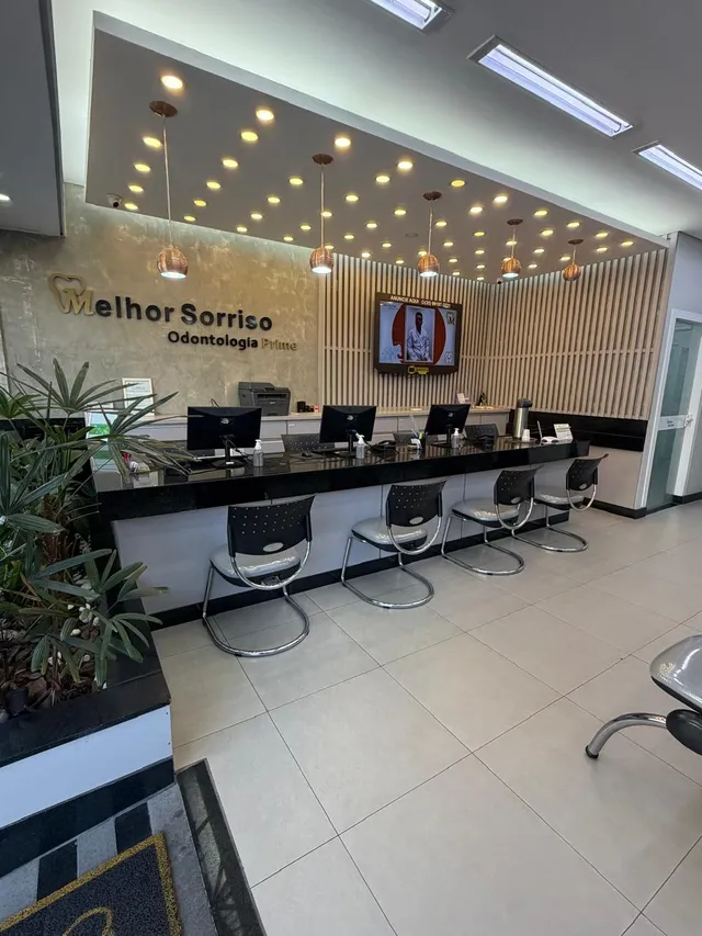 Recepção com balcão escuro, painel de ripas de madeira e o letreiro Melhor Sorriso Odontologia Prime na parede