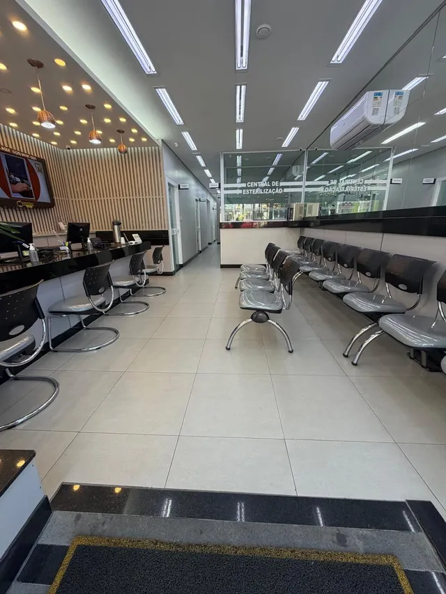 Sala de espera ampla, com fileiras de cadeiras, piso claro e iluminação embutida no teto